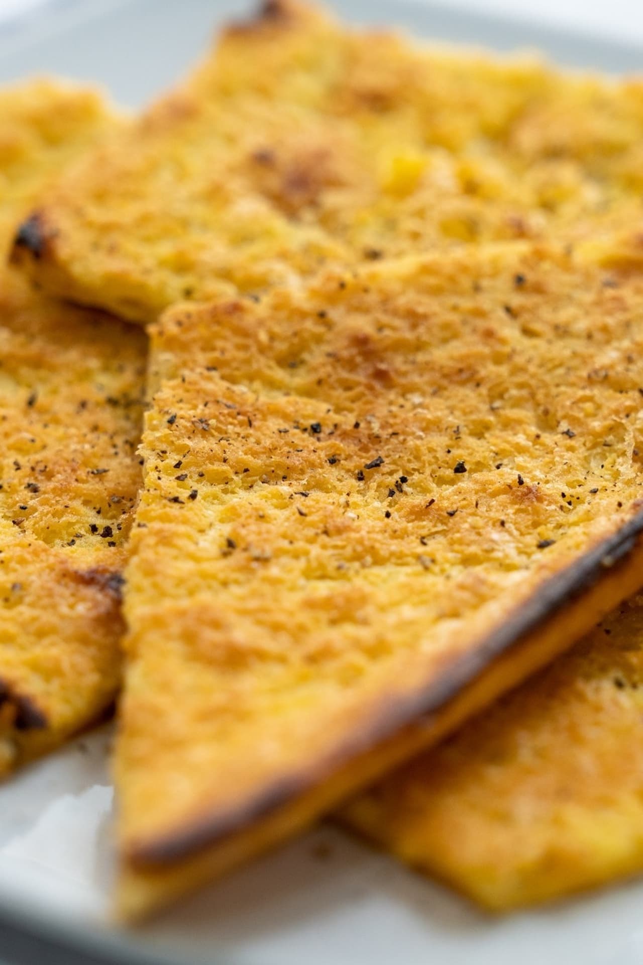 Triangoli di farinata di ceci dorata con bordi croccanti e una spolverata di pepe nero.